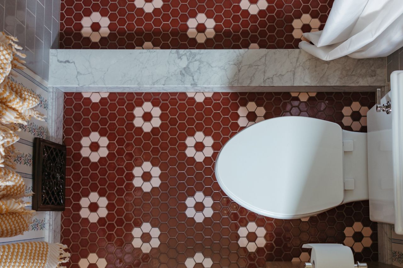 Overhead shot of a bathroom and shower with sienna-colored hexagon tiles with a pink hexagon floral pattern. 