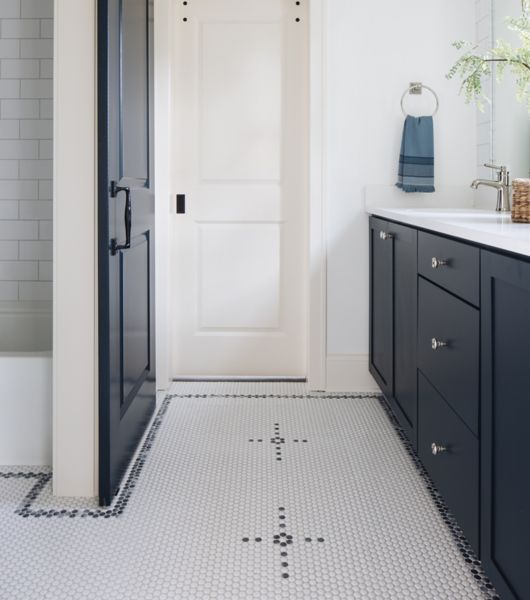 Bathroom with black and white sink vanity, white walls and door.