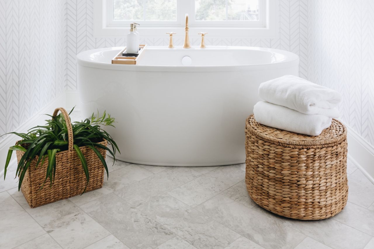 This bright white bathroom features large-format white marble tile in a herringbone pattern. 