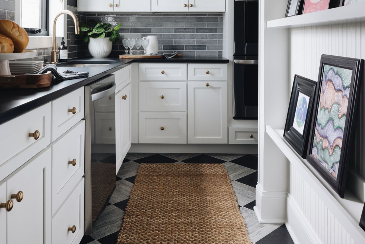 This elegant kitchen features dark grey brick-look subway tile backsplash and a checkerboard silver and black limestone tile floor.