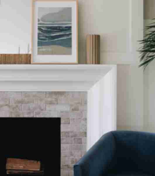 In this transitional living space, a traditional-looking fireplace is modernized with a streamlined white mantel and whitewash-effect brick-look tile on the front of the fireplace.