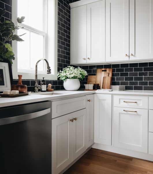 Kitchen with black tile wall and white cabinetry.