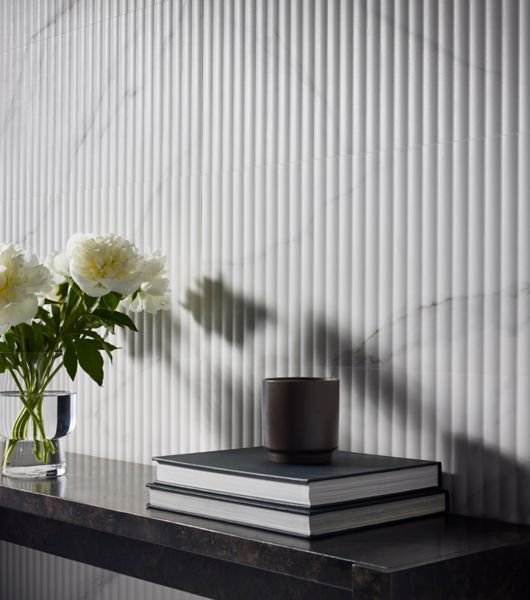 A fluted marble-look tile wall and a small shelf.