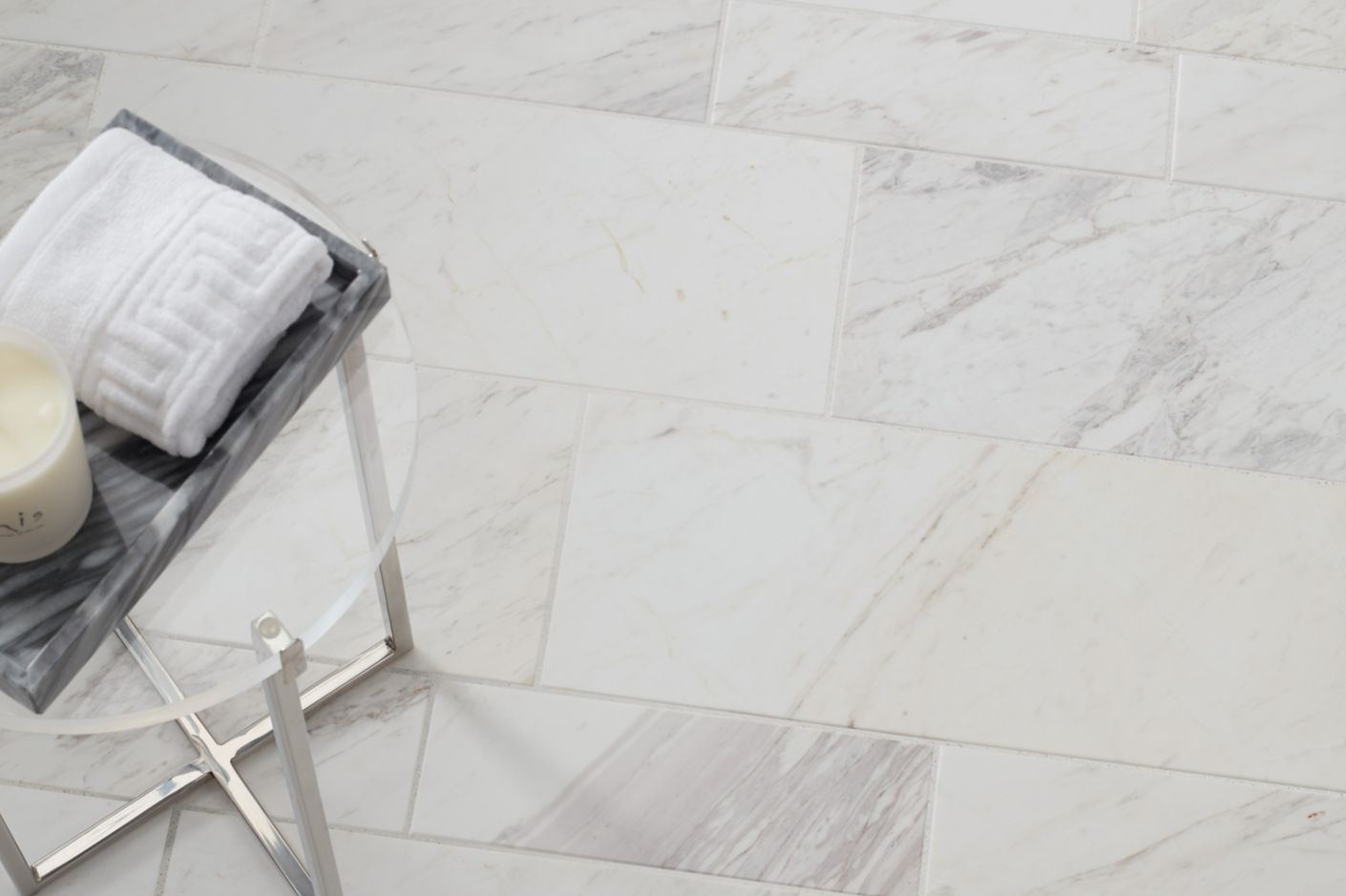 Aerial shot of a white marble subway tile floor with a small table.