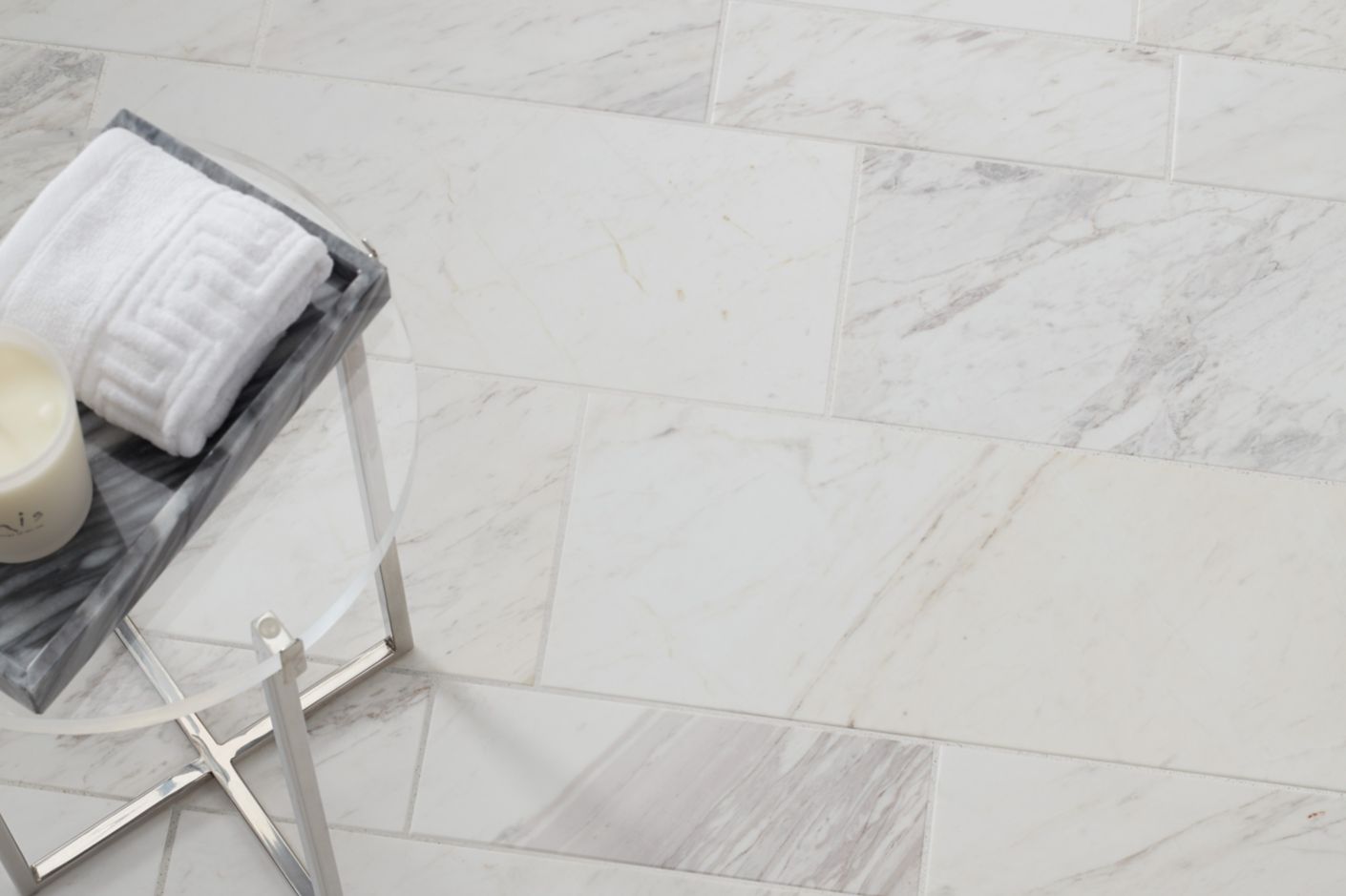 Aerial shot of a white marble subway tile floor with a small table.
