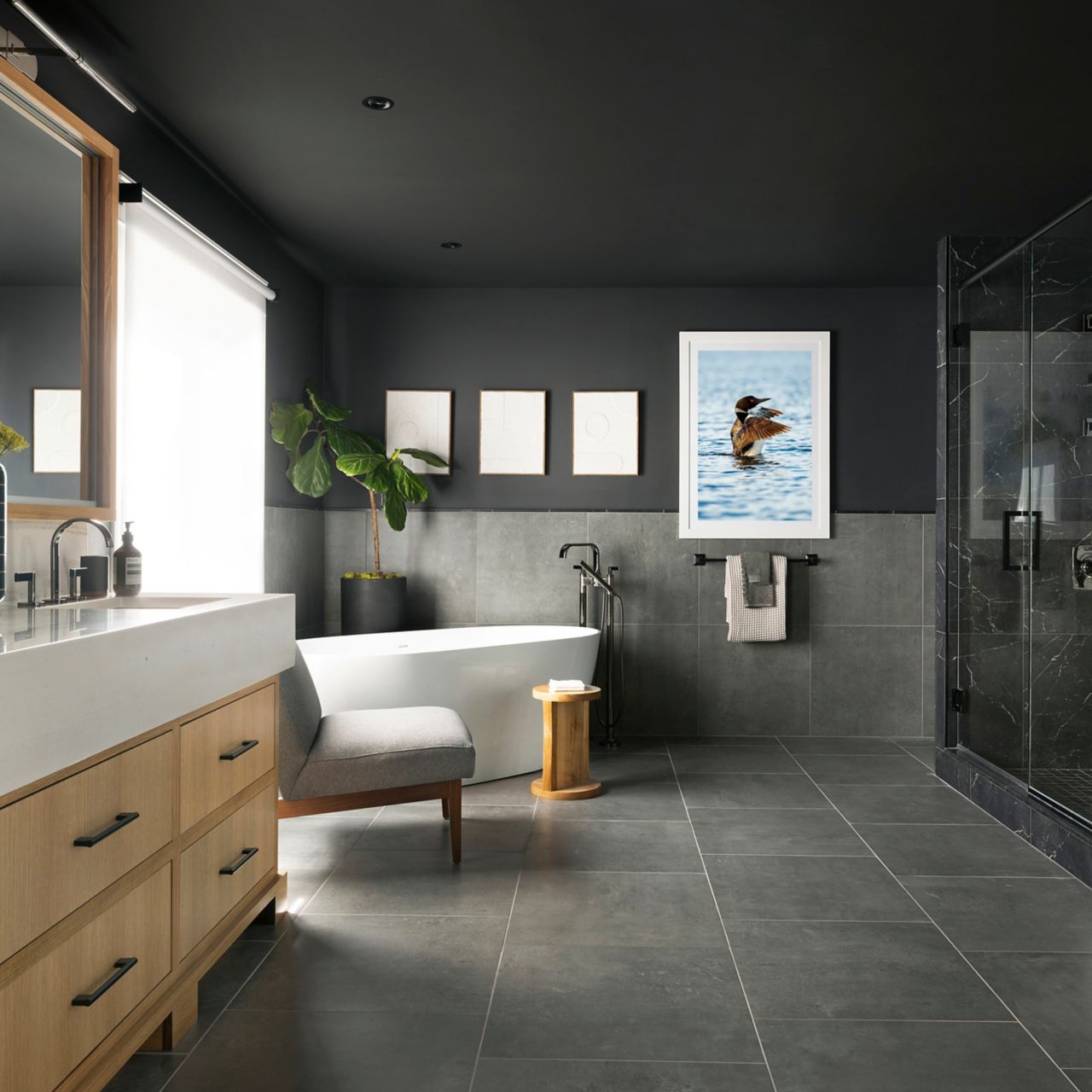 A modern bathroom with large-format grey floor and wall tile and a shower featuring black with white veined marble-look tile.