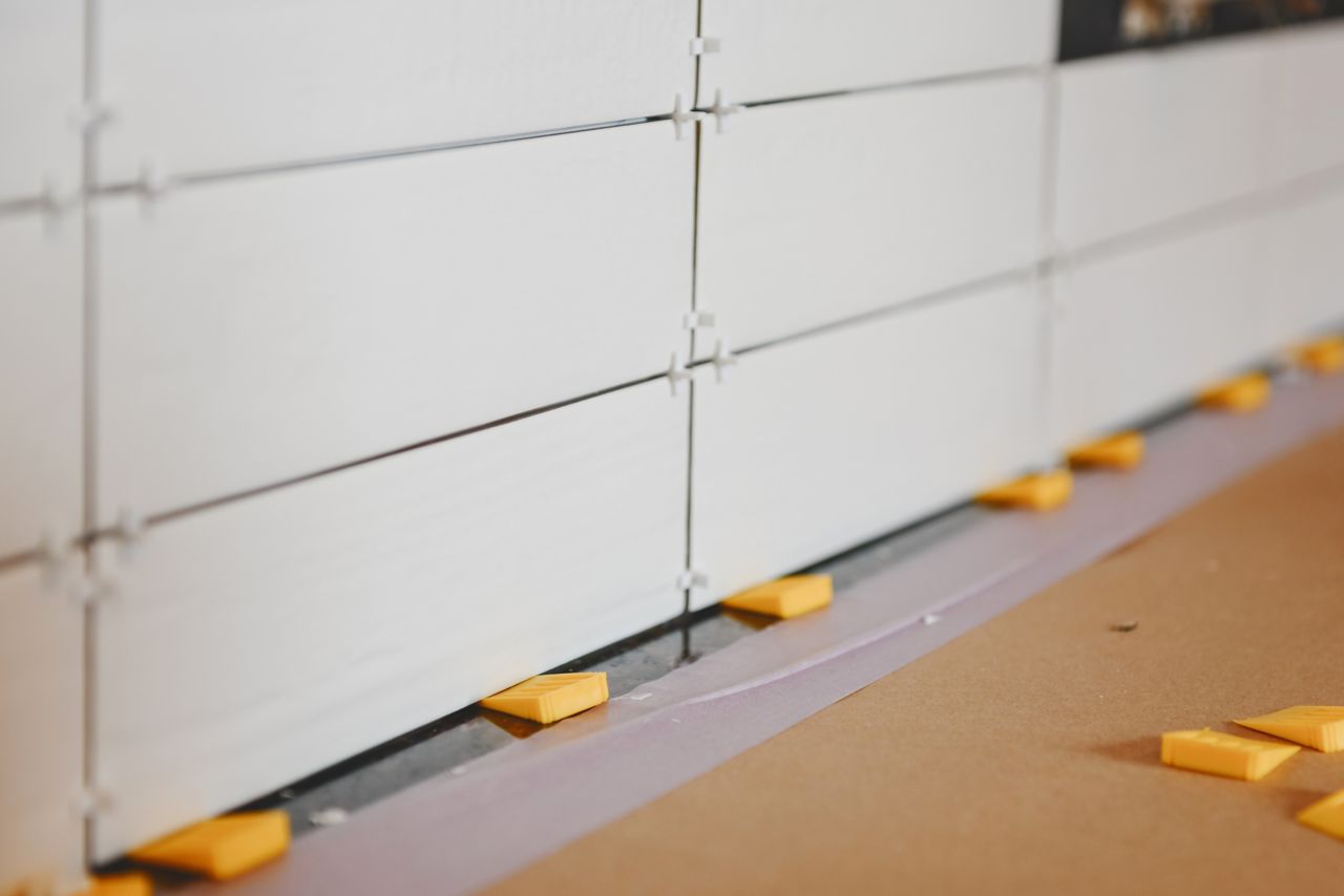 Using tile spacers between the kitchen counter and first row of a subway tile backsplash ensures the correct width for the expansion gap.