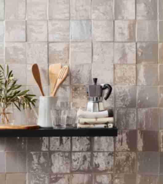 This kitchen wall is covered in glossy beige ceramic handmade Moroccan tile. Each of the square tiles has subtle variation in color and texture, which adds depth to an otherwise simple tiled surface.