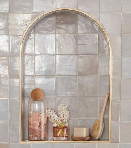 Cream-colored tile niche with decorative bottles and brush.
