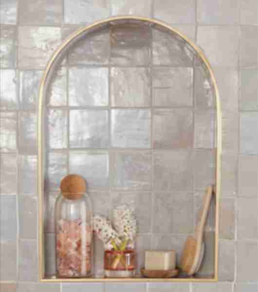 Cream-colored tile niche with decorative bottles and brush.