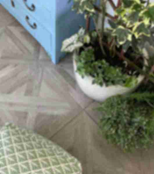 Brown-grey wood-look porcelain floor tile reminiscent of a classic parquet floor. With plant and blue dresser.