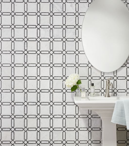 Wall tiled in Ava with Marquina marble mosaic tile features a white tile with subtle grey veining and black Marquina circular and rectangular accents that form a chain-link design reminiscent of jewelry.  Used as accent wall behind pedestal sink and oval mirror hung above.