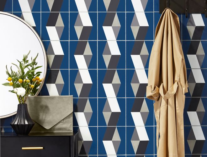 Entry way with focus on patterned cement tile accent wall in blue, white, light and dark grey.  Wall has coat rack in black to match side table with mirror.