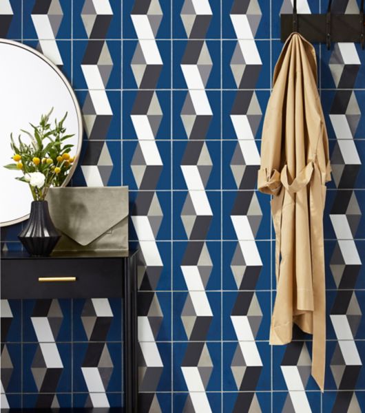 Entry way with focus on patterned cement tile accent wall in blue, white, light and dark grey.  Wall has coat rack in black to match side table with mirror.
