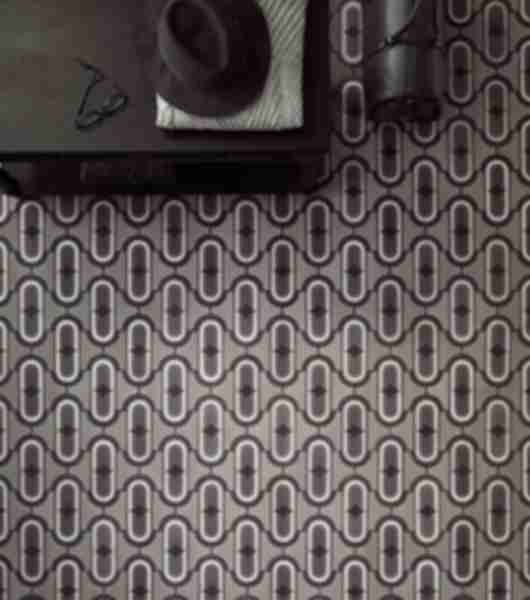 Inspired by the shape of a belt, loop and buckle. This floor tile featured was transformed into an abstract design consisting of concentric ovals in tonal greys and a central diamond design. 