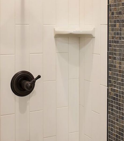 White shower wall with corner shelf and soap dish.