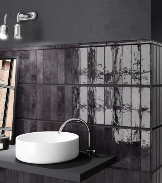 A modern bathroom sink with a glossy black subway tile backsplash.