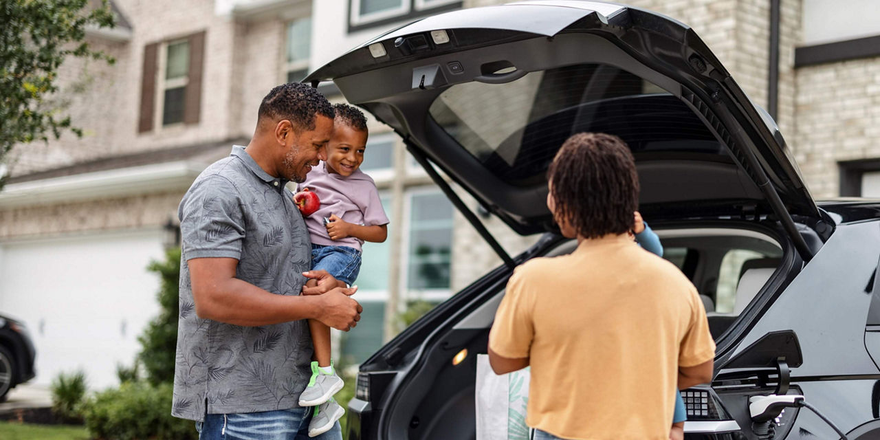 People loading bags into a vehicle parked in front of a residential home.