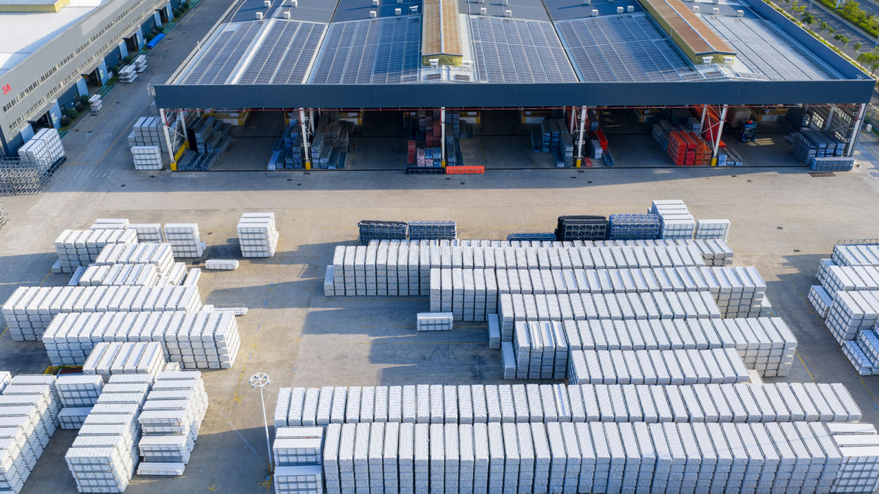 Aerial view of outdoor storage yard with neatly stacked goods beside modern industrial factory.