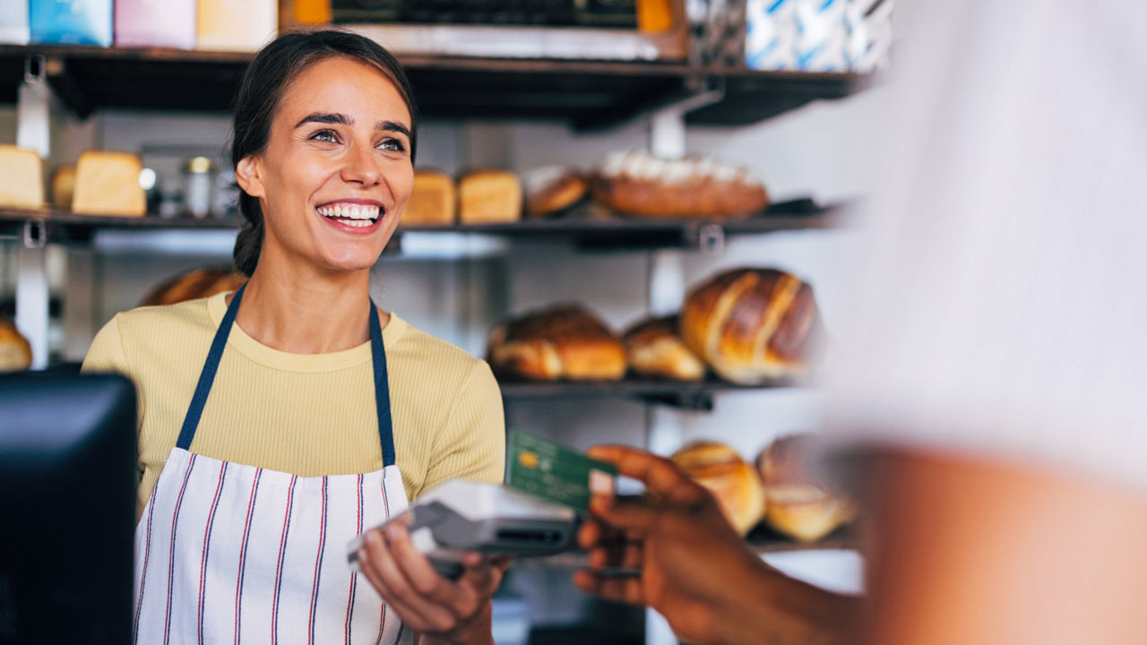 Propriétaire d’une petite entreprise acceptant un paiement par carte dans une boulangerie.