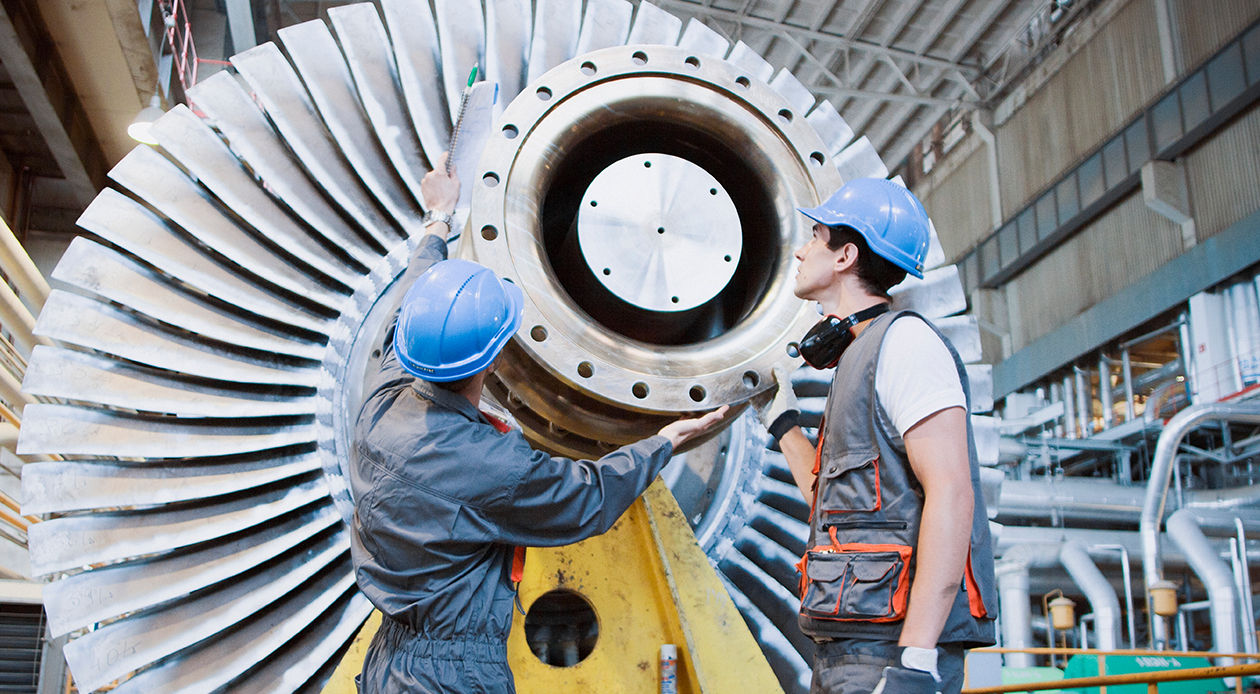 Travailleurs industriels inspectant et entretenant un grand composant de turbine dans une usine