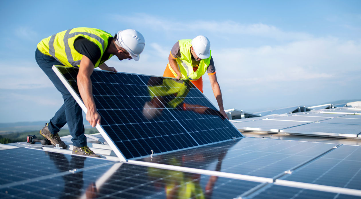 Travailleurs installant un panneau solaire sur un toit.