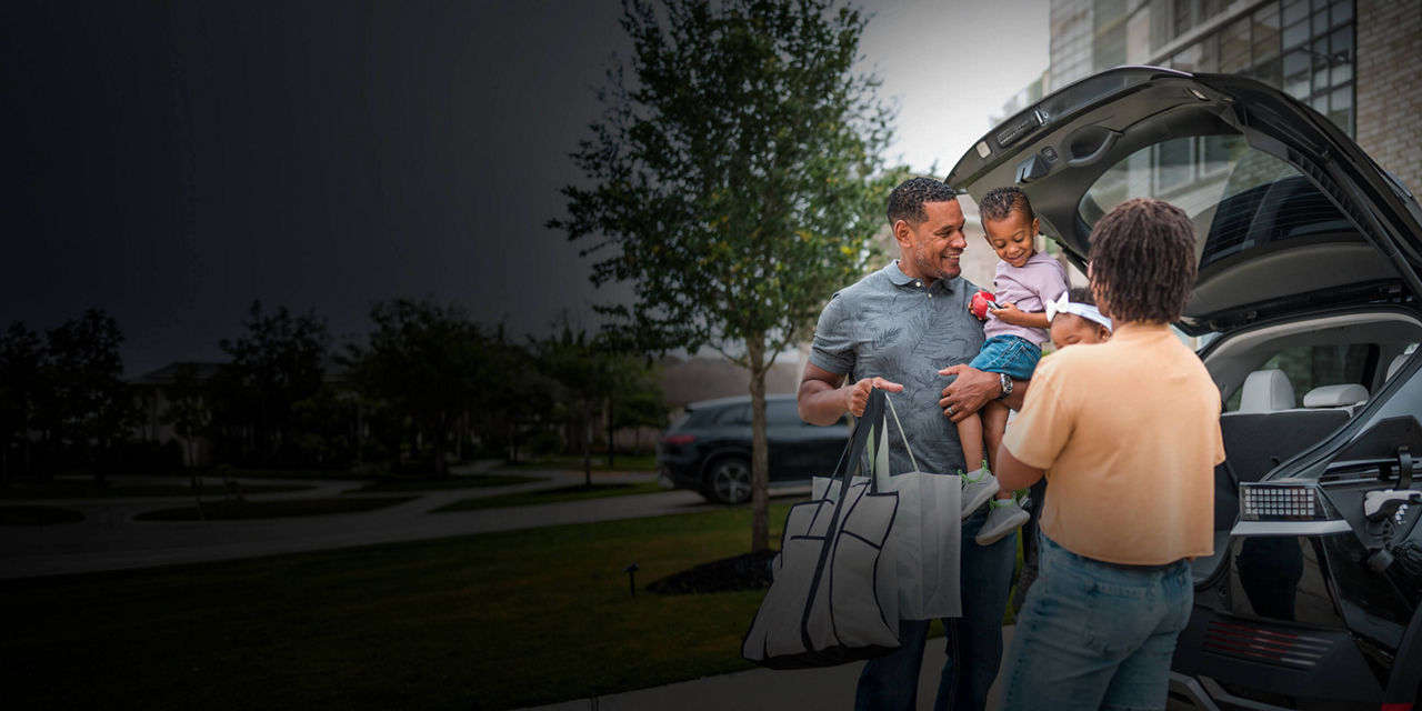 Family unloading shopping bags from an SUV outside a residential home.