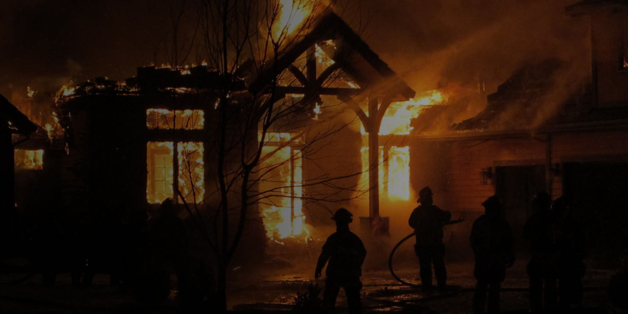 Pompiers intervenant lors d’un incendie résidentiel alors que les flammes ravagent la maison pendant la nuit.