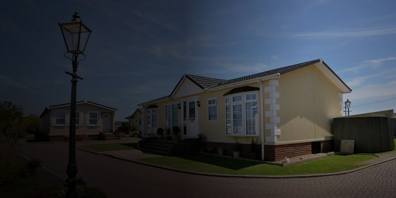 Manufactured home in a residential community with landscaped grounds and a paved roadway.