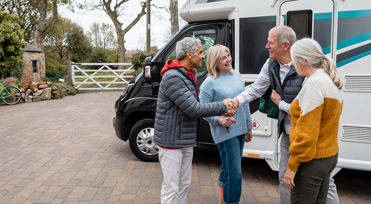 A person handing another person keys to the parked rv for RV- sharing insurance