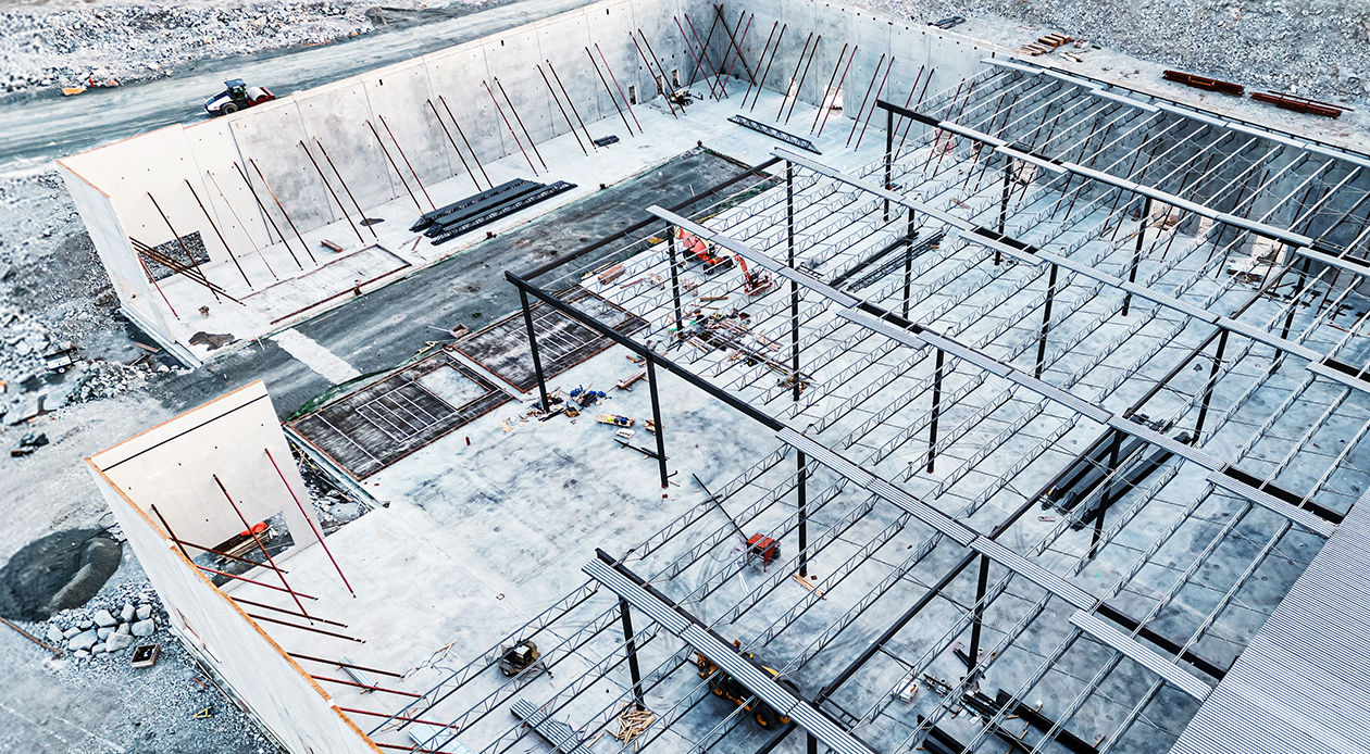 Aerial drone view of warehouse under construction in the winter with snow blanketing the entire site. 