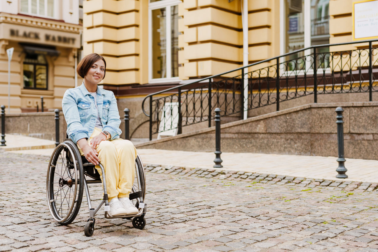 Brunette woman sitting in wheelchair on city street