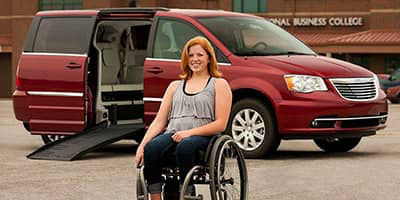 girl in a wheelchair in front of her Chrysler Town and Country handicapvan mobility vehicle