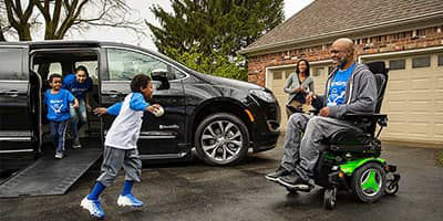 A family with a BraunAbility Chrysler Pacifica Mobility Vehcile in a driveway