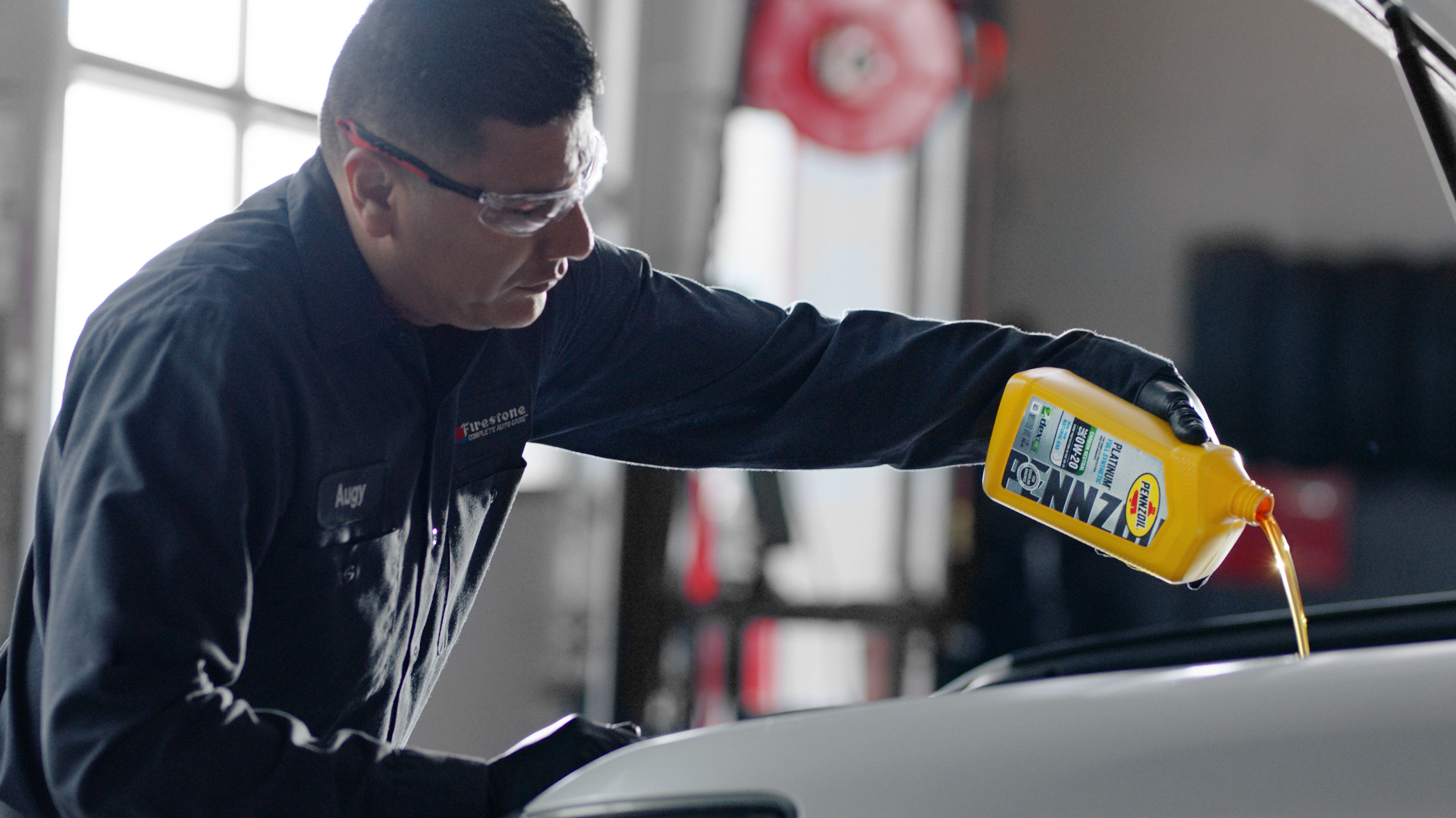 Vehicle mechanic filling vehicle up with oil