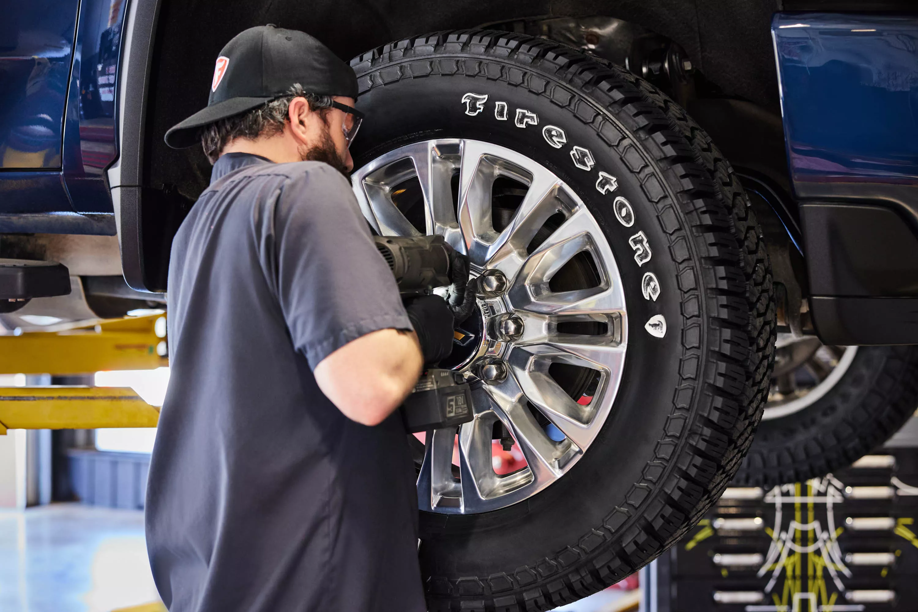 Male Firestone techician mounting a tire to a vehicle. 