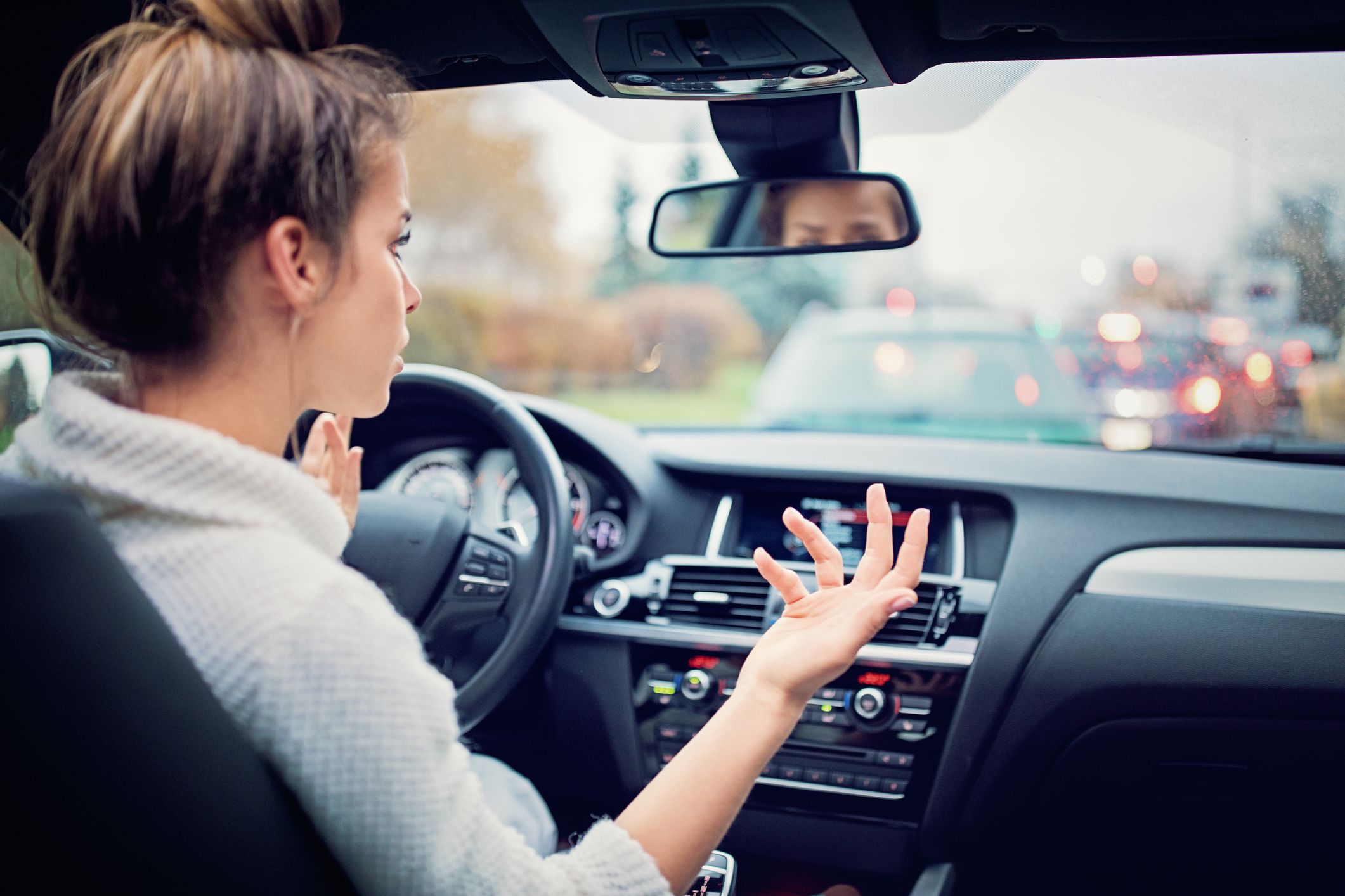 Frustrated girl waiting in traffic jam during rainy weather