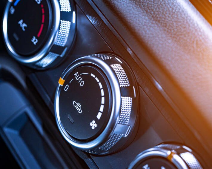 Three knobs on car air conditioner with sun streaming in at top right corner