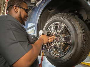 A Tires Plus technician in the shop adjusting and inspecting a vehicle's tire.