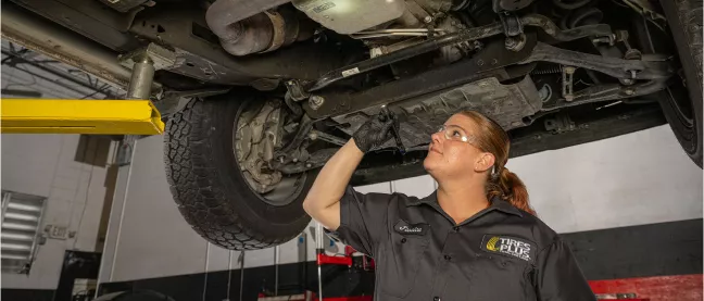 An auto technician reviewing vehicle inspection details on a tablet.