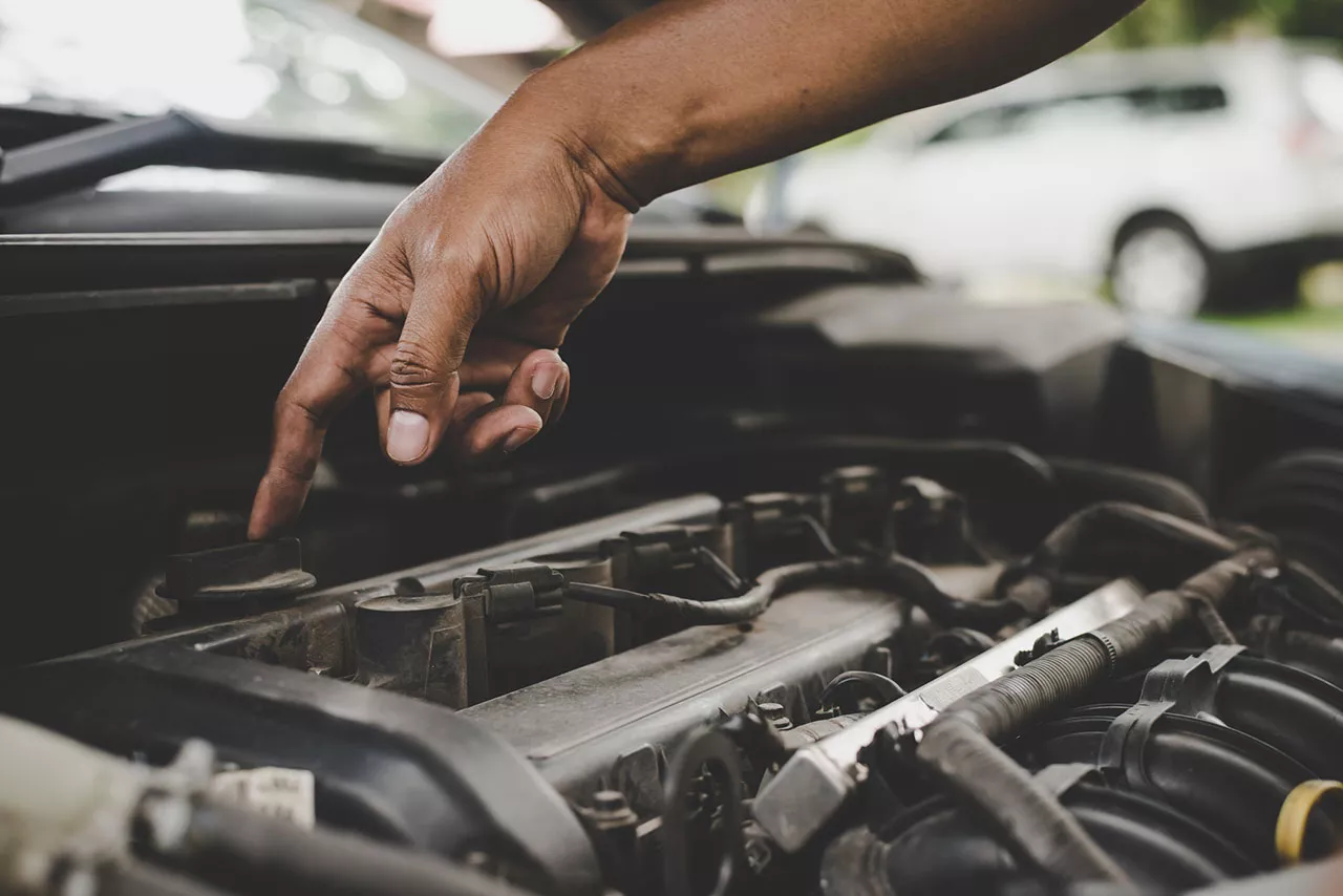 Close-up of technician working on components inside a car engine bay.