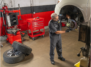 A technician inspecting the wheel axle of a lifted vehicle in a pro garage.