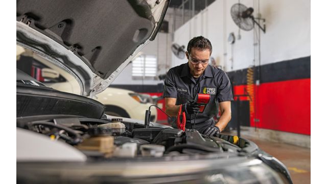 A technician testing a car battery.
