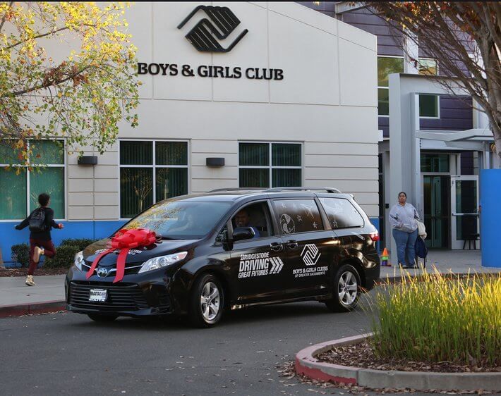 Black Bridgestone van delivered to Boys & Girls Club with a bow on top
