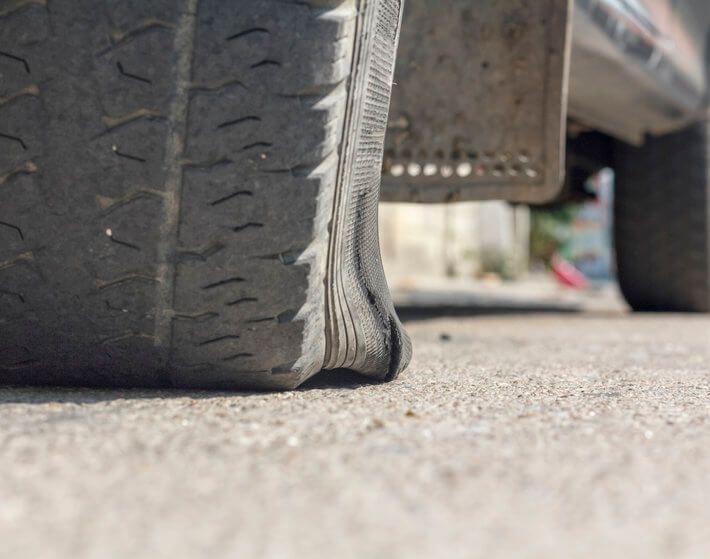 Close up of blown car tire, car stopped on roadway