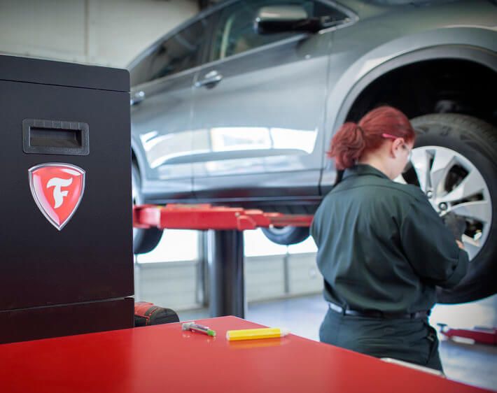 Brianna Fernando, Firestone technician, working on a car next to the Firestone logo