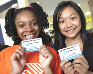 Two girls in Boys and Girls Club of America, holding up their membership cards