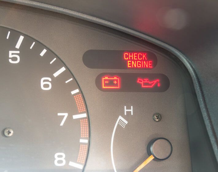 Close up of car dashboard with check engine light, oil light, and battery indicator lights on