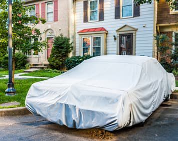 Car covered in sheet sitting in driveway