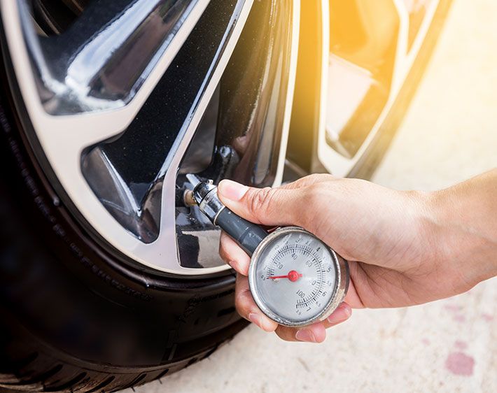 Man checking tire pressure using hand gauge